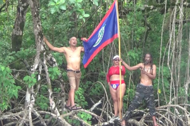 Three Members of the BTV holding the NATIONAL Flag  on top Mangroves near the Sarstoon Island